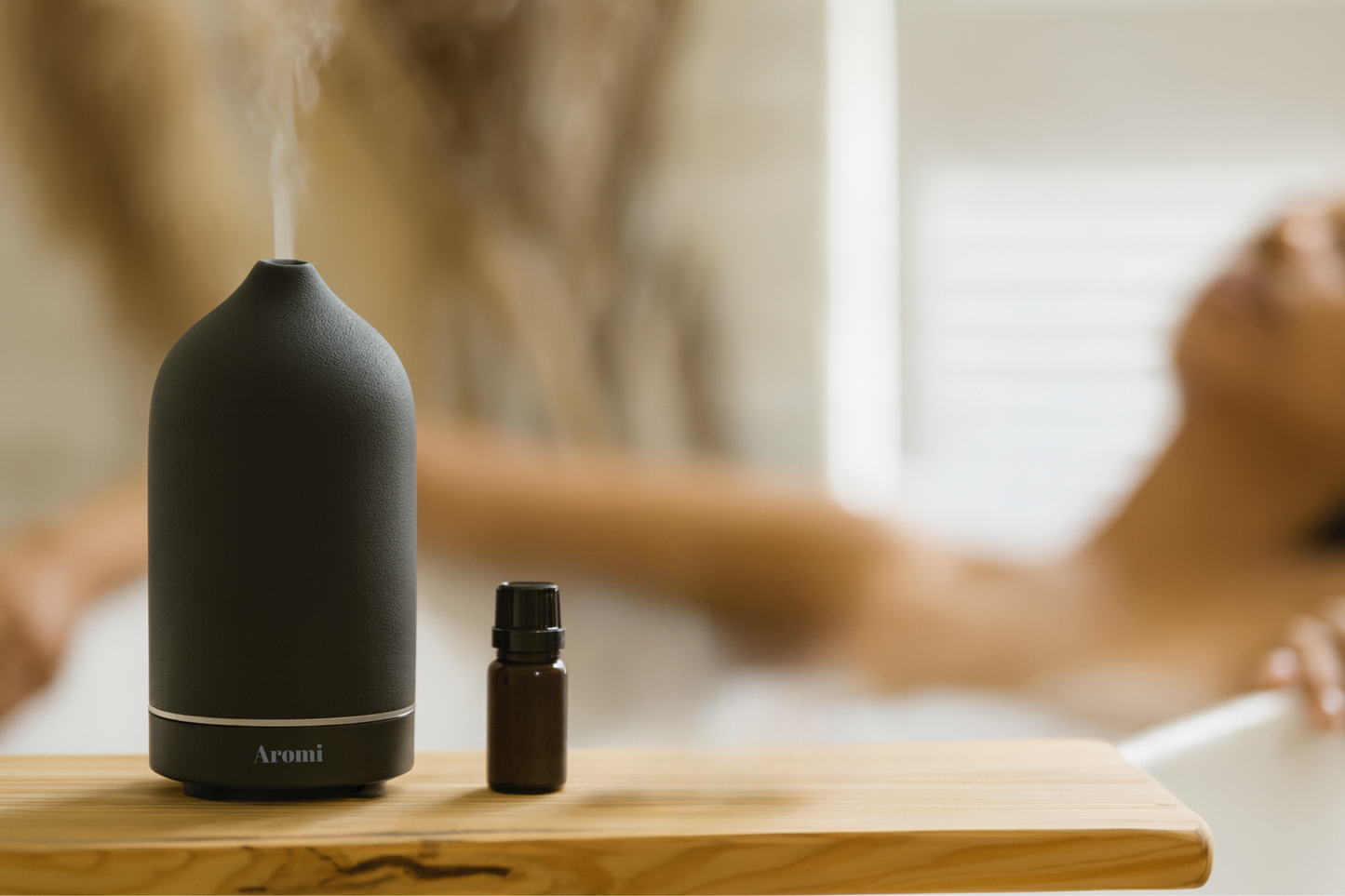 Svart trådlös keramisk diffuser och eterisk olja med kvinna som slappnar av, frontvy